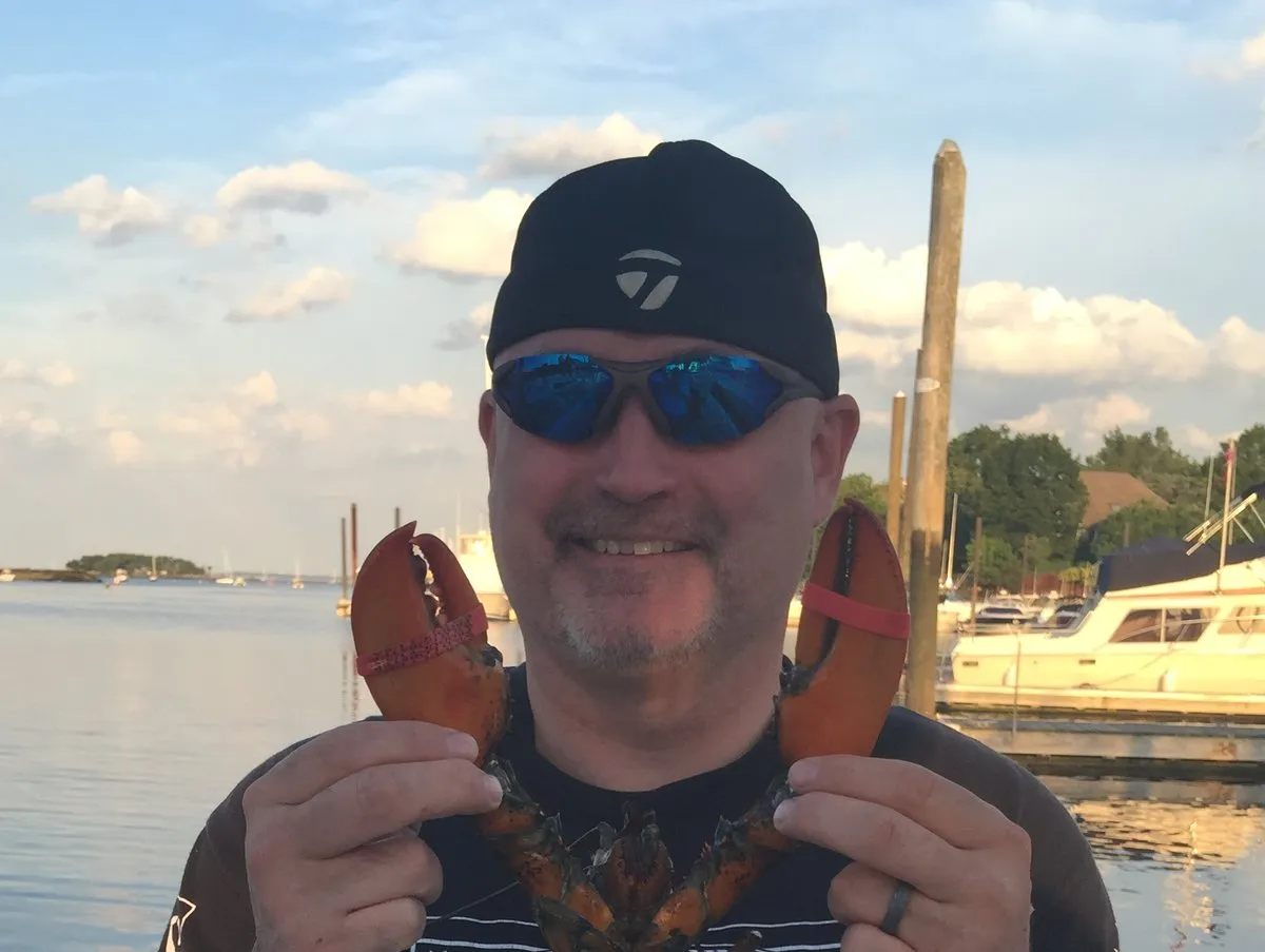 Bryan Collins on a boat in the Northeast, holding a lobster